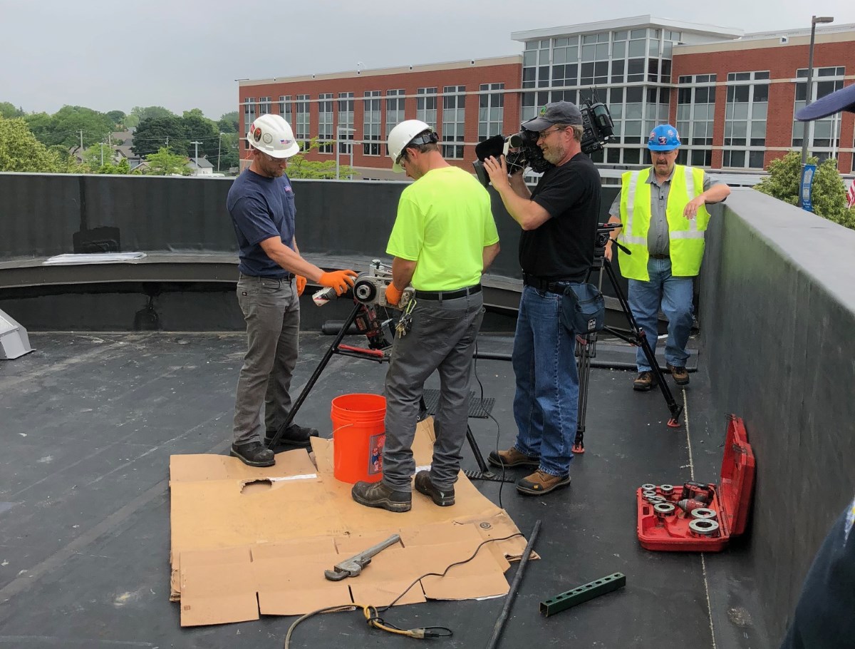 Dillett Mechanical Service Technicians threading gas pipe while being filmed for Wisconsin Builds TV Show